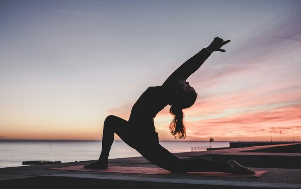 Athlete stretching beside the water at sunset